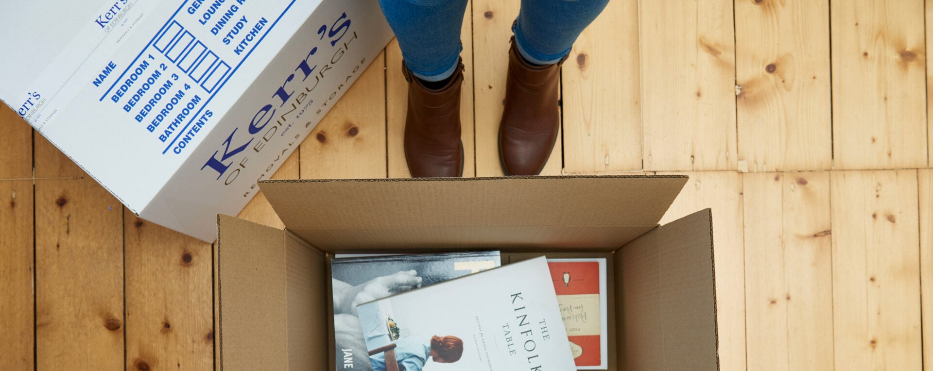 Close-up of a Kerr’s of Edinburgh moving box being packed with books, symbolising the care and detail customers appreciate in Kerr’s removals service.